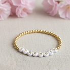 Bracelet with 'STRENGTH' beads on a light background with pink flowers