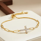 Gold bracelet with a cross charm on a white surface