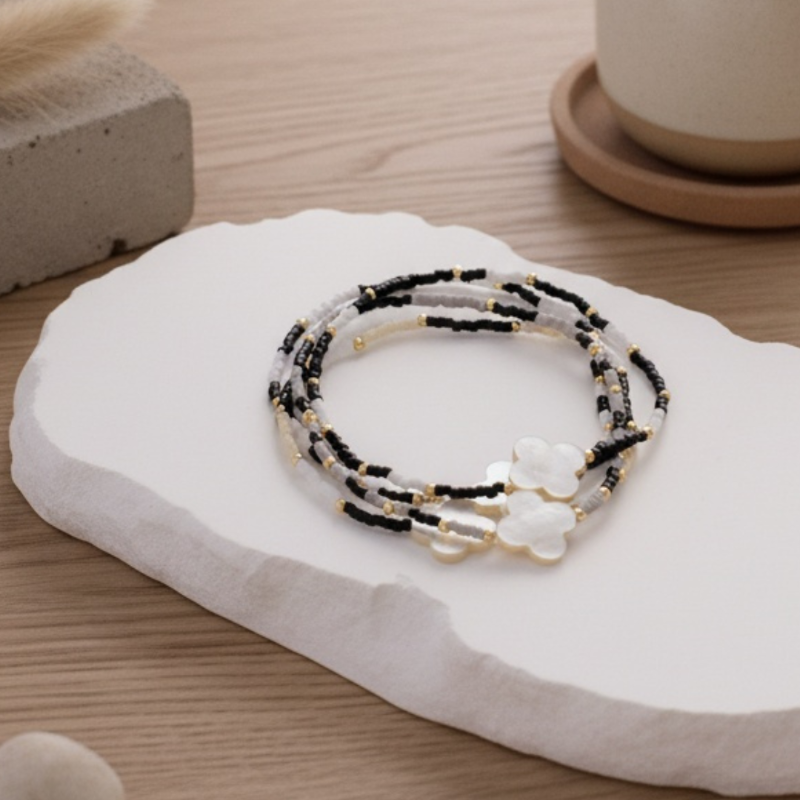 Set of beaded bracelets on a white stone surface with a wooden background