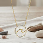 Gold necklace with a wave design pendant on a neutral background