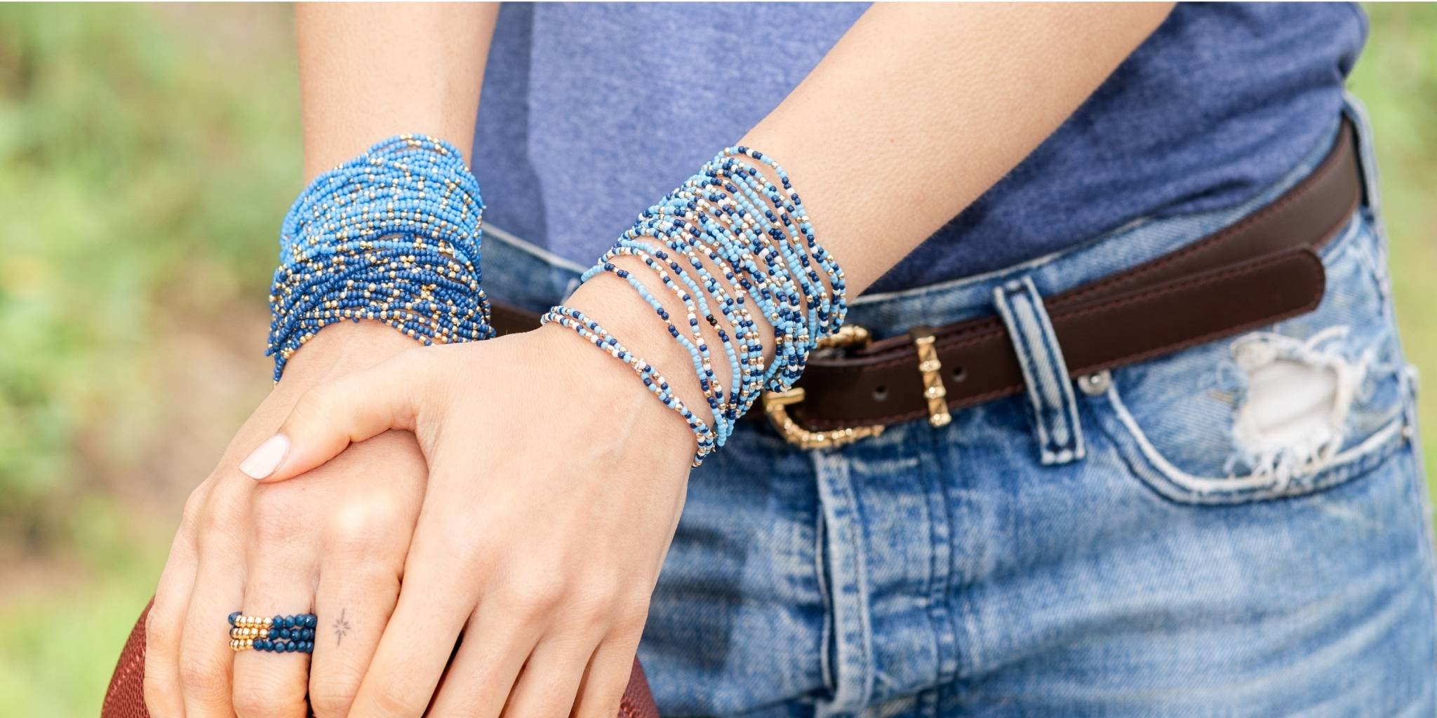 Person wearing multiple beaded bracelets on a blurred natural background