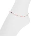 A delicate beaded ankle bracelet with small multicolored cylindrical beads, displayed on a white mannequin ankle.