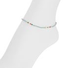 A delicate beaded ankle bracelet with a light blue-gray base and small multicolored beads, displayed on a white mannequin foot against a white background.