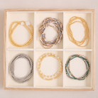 Set of beaded bracelets in a wooden box on a beige background